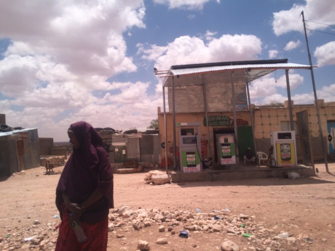 a woman waits for a bus at a gas station